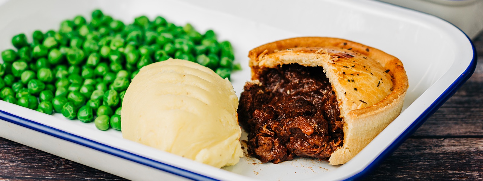 A Hull Pie steak pie cut open on a plate with mash and peas